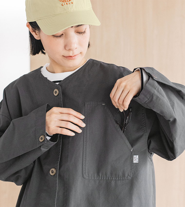 ャコールのライトコートの胸ポケットに眼鏡を出し入れする様子のディテール画像