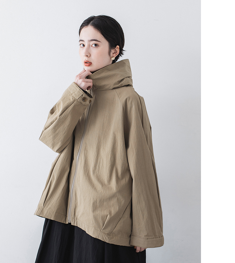 グレイベージュのジップジャケットを着用した正面ポートレートカット（襟元に手を添えたポーズ）