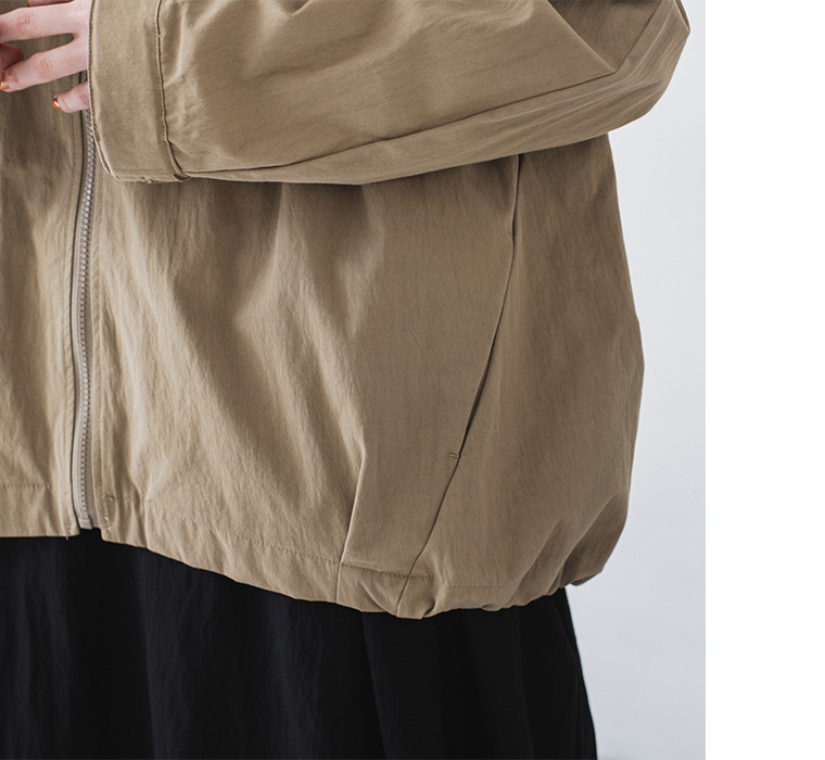 グレイベージュのジップジャケットの裾とポケットディテールのクローズアップカット