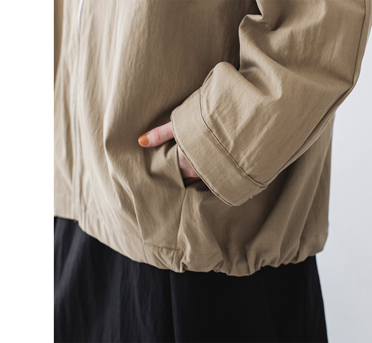 グレイベージュのジップジャケットのポケット使用時のディテールカット（右手をポケットに入れた様子）