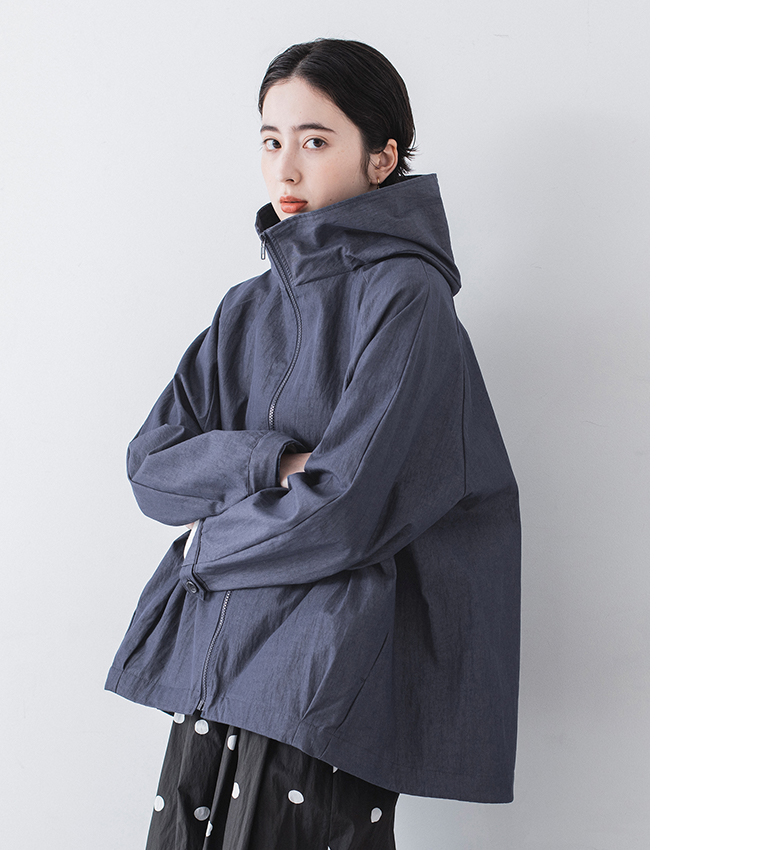 ネイビーのフード付きジップジャケットとドット柄ワイドパンツを着用し、腕を組んだポーズの正面カット