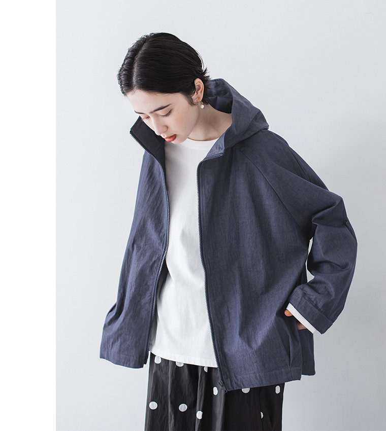 ネイビーのフード付きジップジャケットを白Tシャツとドット柄ワイドパンツに合わせたリラックスコーデ（ポケットに手を入れたポーズ）