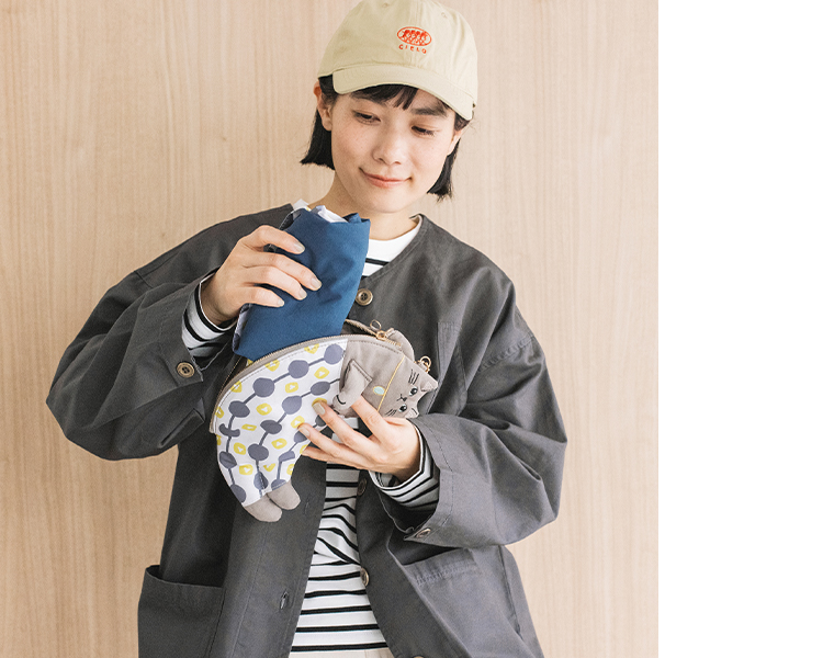 aonecoのネコテコ リュックトートを肩掛けし、中身を取り出す使用イメージ