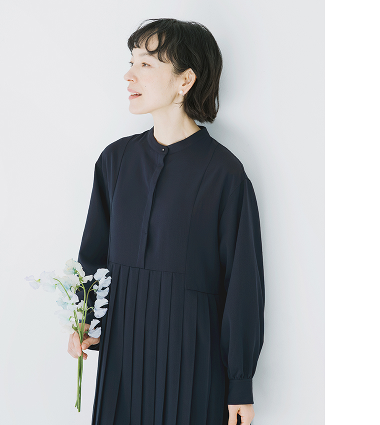 ネイビーのプリーツワンピースを着用し、白と薄紫の花束を持った正面コーディネート