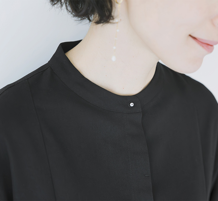  ブラックのプリーツワンピースの襟元とパールのイヤリングのディテールアップ