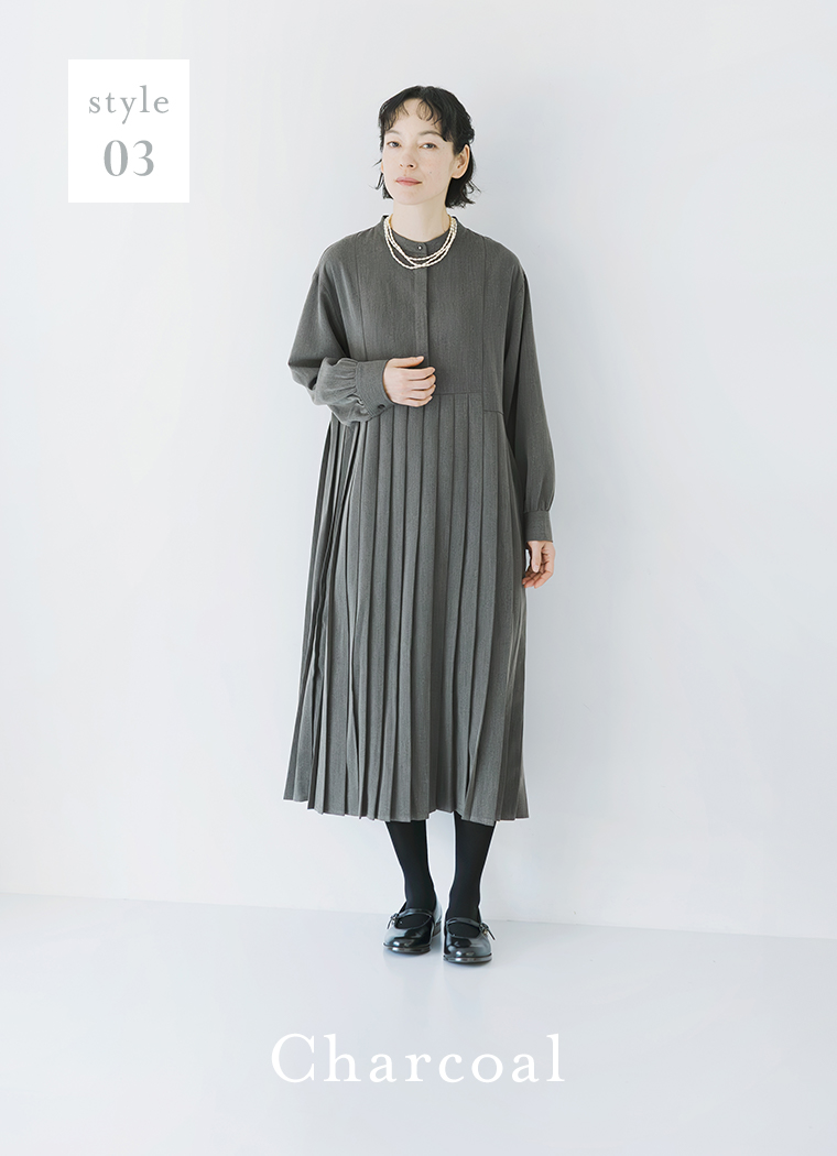 チャコールのプリーツワンピースを着用し、黒タイツとシューズを合わせた全身コーディネート（style 03・Charcoalの文字入り）