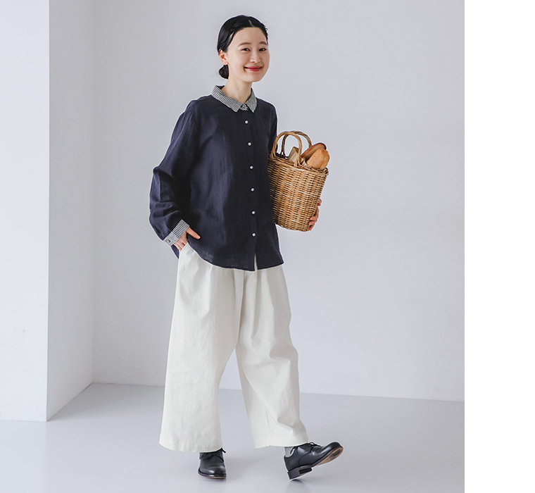 コットンダブルガーゼシャツを着用したモデルがかごバッグを手に持って歩いている全身カット