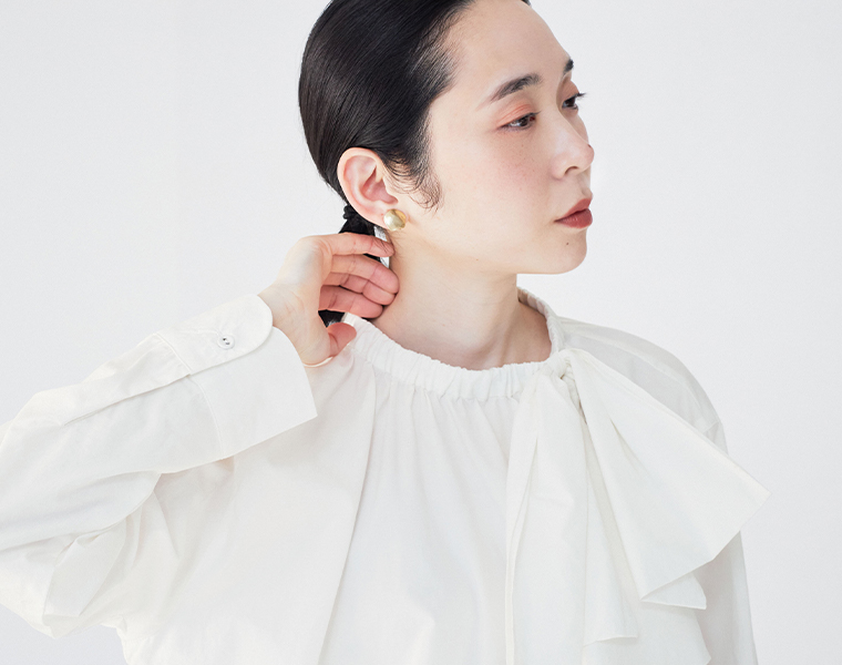 nop de nod テンセルコットンアシメトリーリボンブラウス（オフホワイト）のリボンディテールをアップで見せた着用イメージ