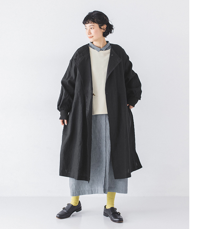 別注｜ヒッコリー ループ釦ワンピースの上にアウターを着用したモデルが立っている全身カット