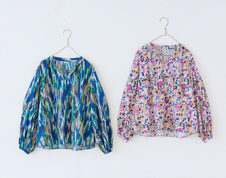 ichiオリジナルアート柄プリントブラウスをゴールドのブルーとピンクをハンガーに掛けた商品画像（白背景）
