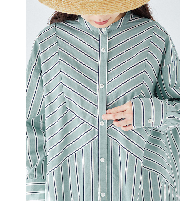 グリーンとホワイトのストライプ柄シャツの胸元ディテール（V字切り替え・バンドカラー・ボタンを指差すポーズ・ストローハット）