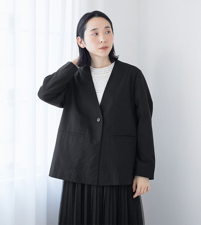 ブラックのジャケットとプリーツスカートを合わせた室内スタイリング