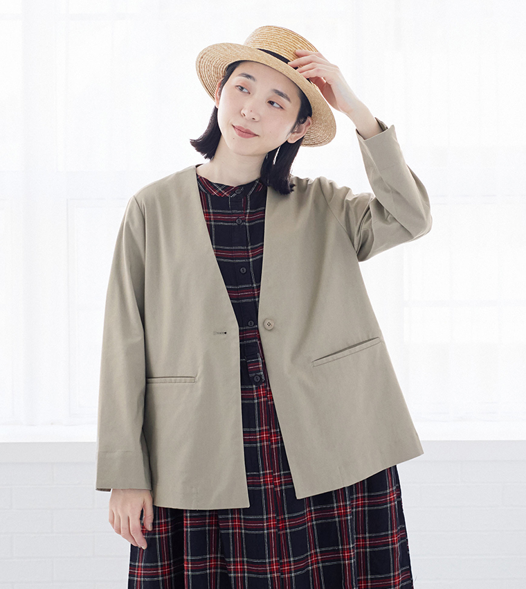 グレージュのジャケットとチェック柄ワンピースを合わせたスタイリング（カンカン帽を手にした姿）