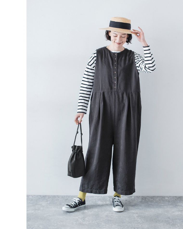 チャコールの2wayオールインワンをボーダーカットソーに重ね、帽子と黒バッグを合わせた全身コーディネート画像