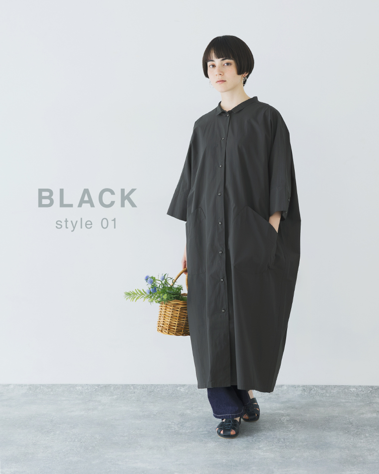 ブラックのドルマンワンピースを着用したコーディネート（花の入ったバスケットを持った正面スタイル）