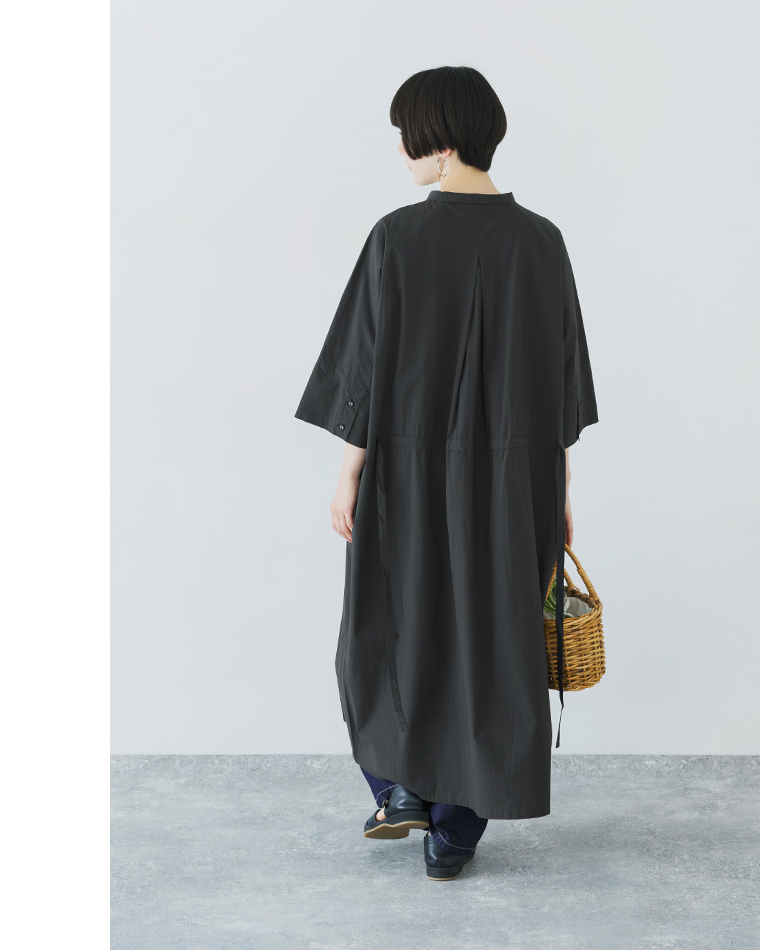 ブラックのドルマンワンピースを着用した後ろ姿のコーディネート（バスケットを手にしたバックシルエット）