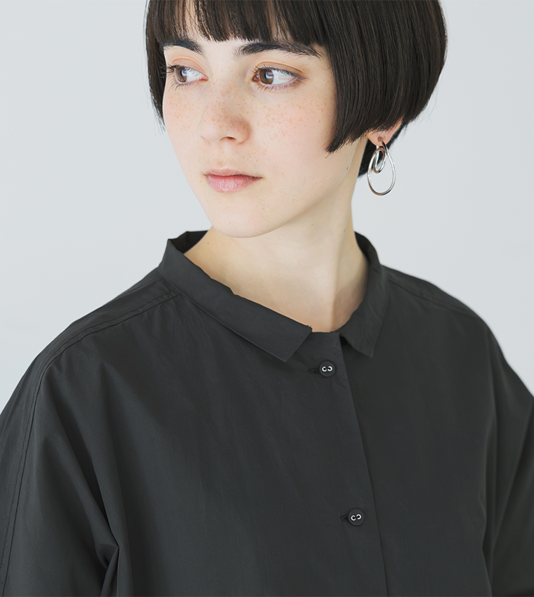 ブラックのドルマンワンピースを着用した上半身のスタイルカット（横向きでイヤリングが見える構図）