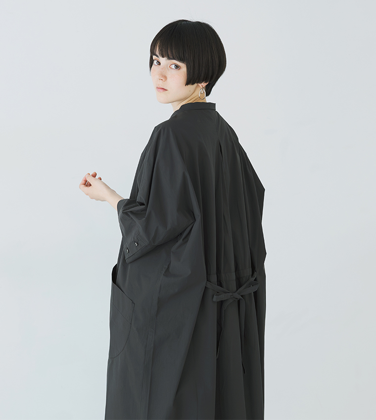 ブラックのドルマンワンピースを着用した横向きの上半身カット（背中のリボンディテールが見える構図）