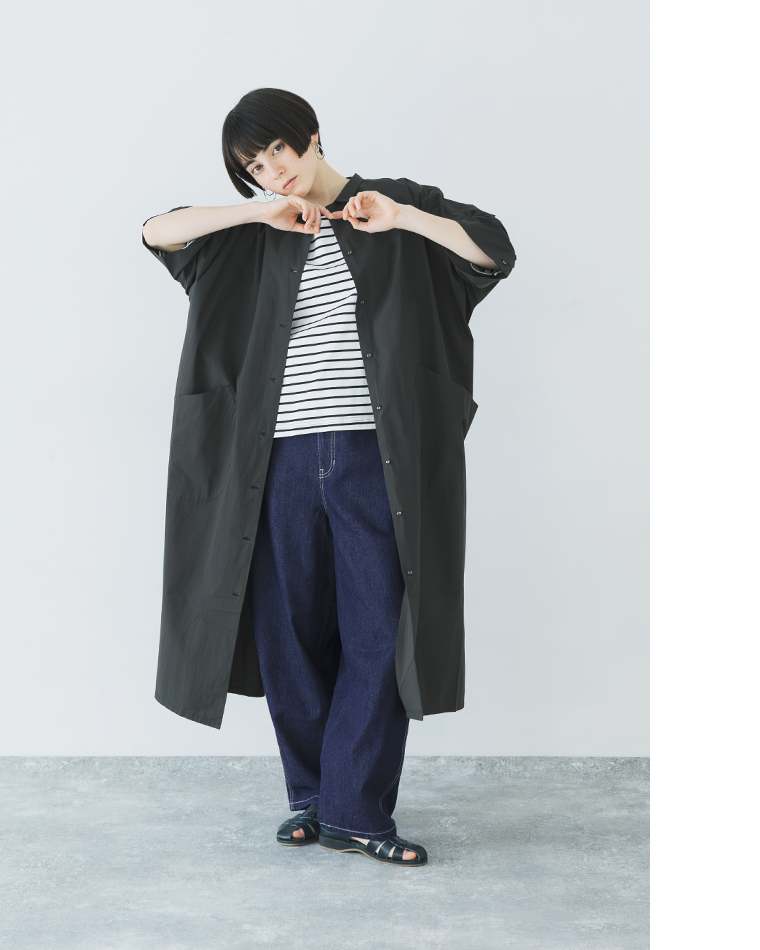 ブラックのドルマンワンピースを羽織ったコーディネート（ボーダーTとデニムを合わせ、襟元に手を添えた正面スタイル）
