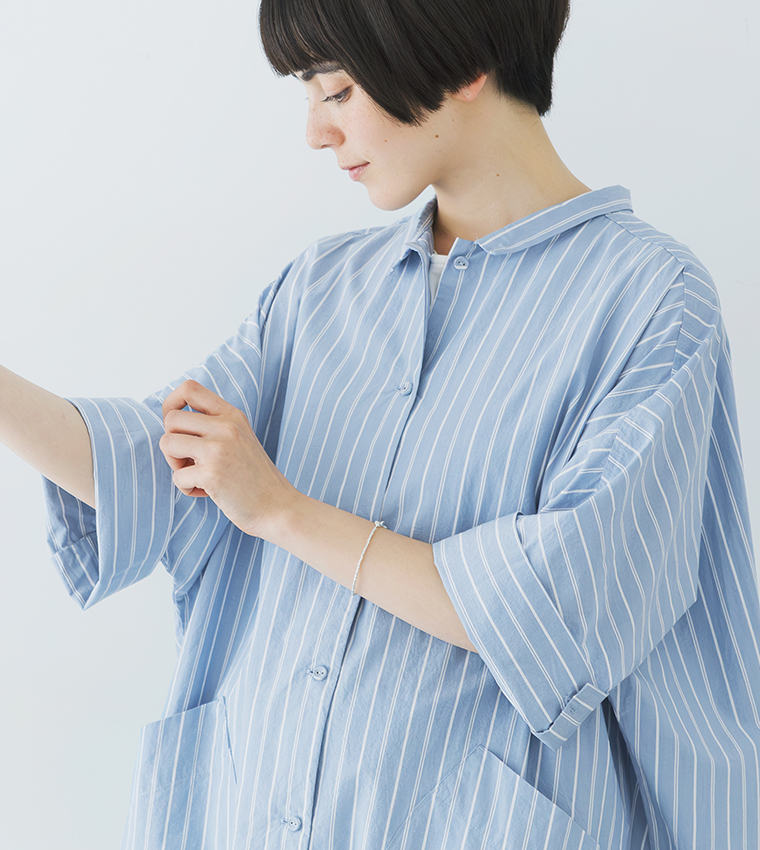 ホワイト×ライトブルーのストライプ柄ドルマンワンピースの上半身カット（袖口を整える手元が見える構図）
