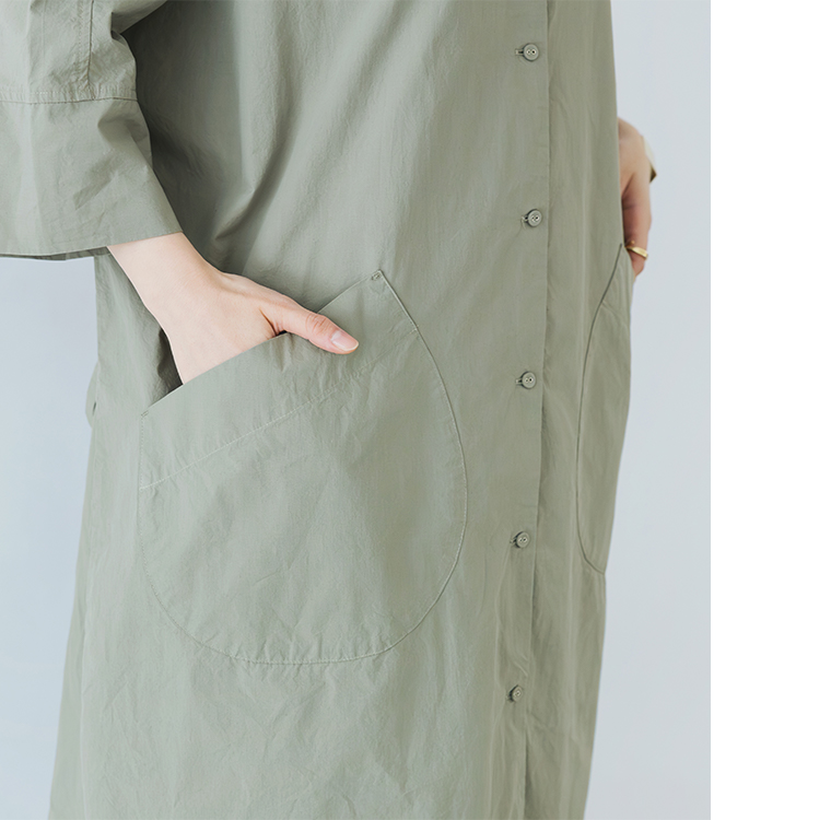 モスグレーのドルマンワンピースのディテールカット（大きめポケットに手を添えた構図）
