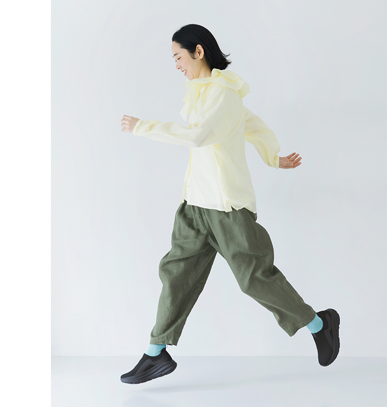 ブラックのニット編みスニーカーを着用して歩くモデルの全身カット