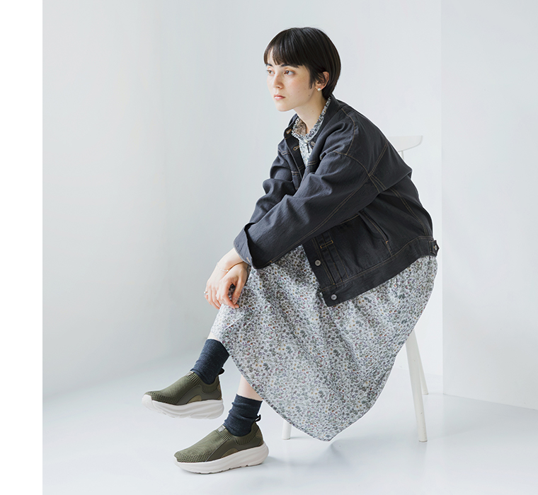 カーキのニット編みスニーカーを着用して座るモデルの全身カット