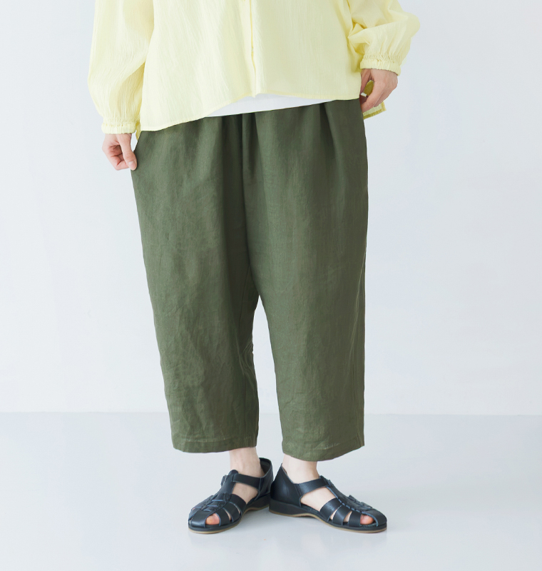 カーキのワイドパンツにライトイエローの長袖トップスと黒のサンダルを合わせた正面コーディネート画像