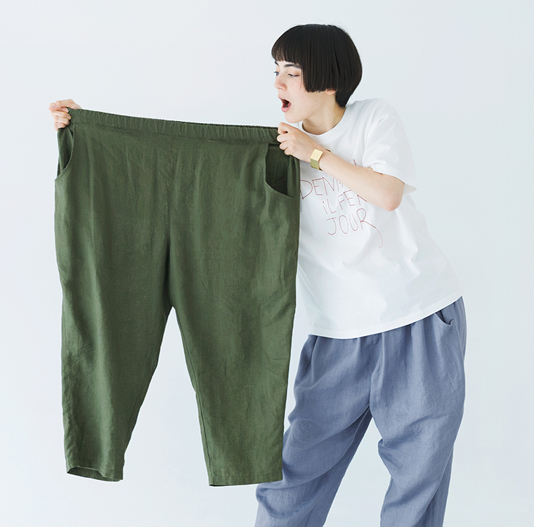 白いロゴTシャツを着た人物が、カーキのパンツを両手で広げて持っている商品イメージ