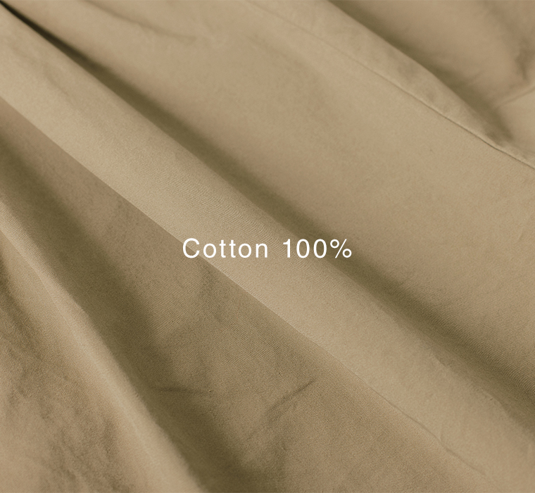 カーキベージュのコットン生地を寄りで写した素材アップ（Cotton 100% の表記入り）