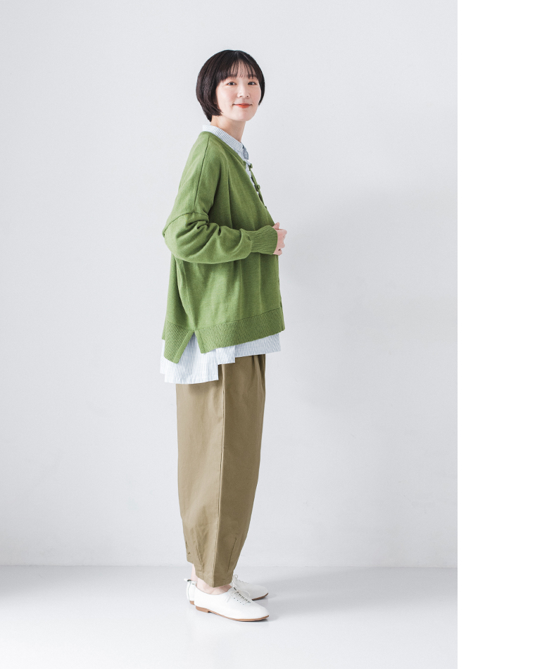 グリーンのニットにストライプシャツ、カーキベージュのパンツと白のシューズを合わせた正面コーディネート