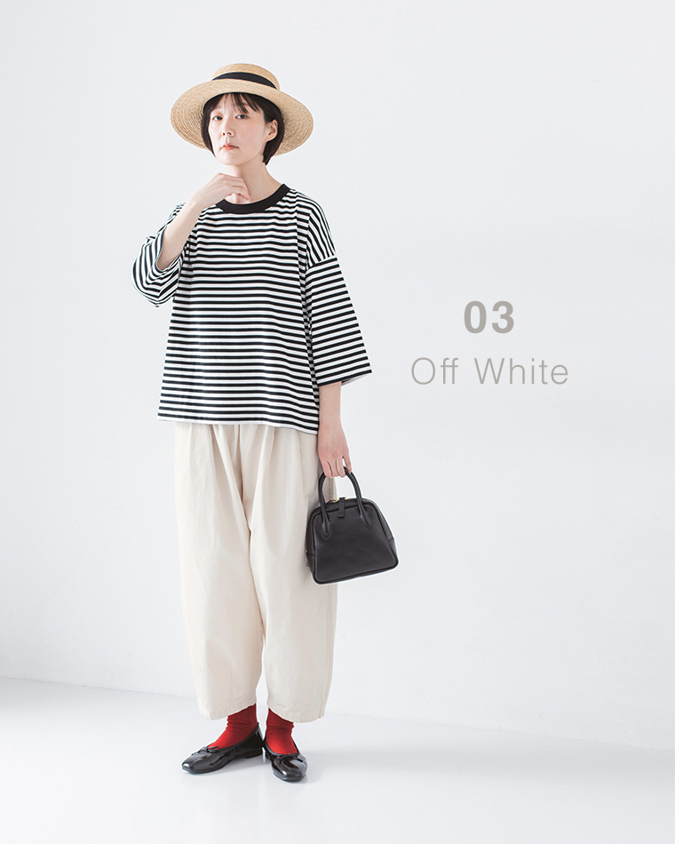 ボーダーの長袖トップスにオフホワイトのパンツ、赤い靴下と黒のバレエシューズを合わせ、ストローハットと黒のバッグを持った正面コーディネート