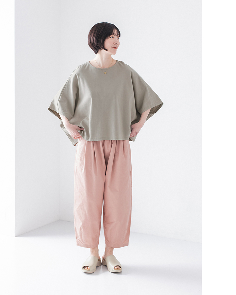 くすみグリーンのトップスにピンクのワイドパンツ、ベージュのサンダルを合わせた正面コーディネート