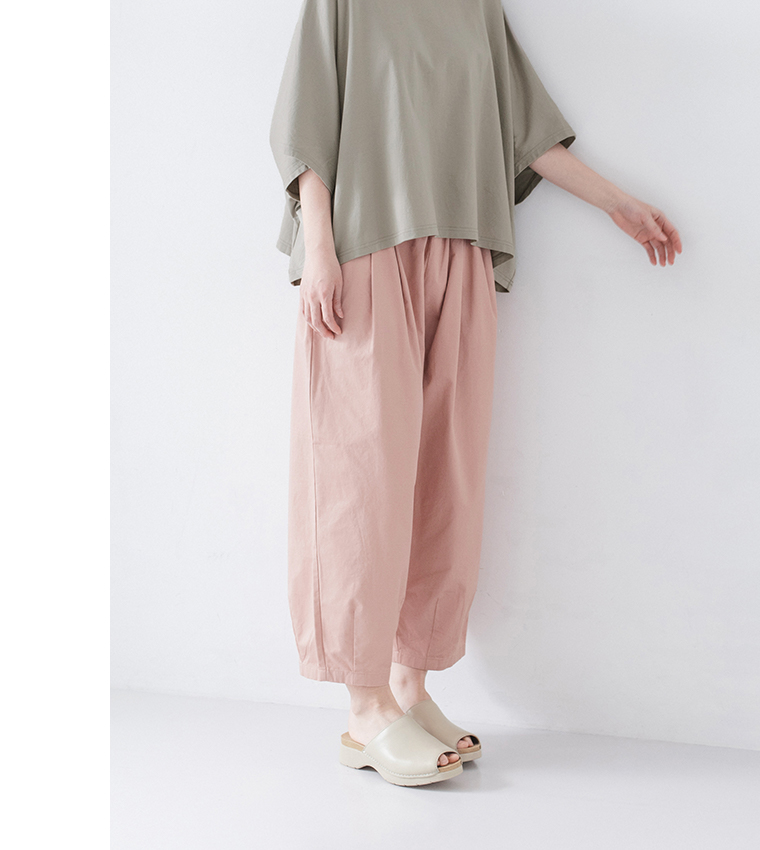 くすみグリーンのトップスにピンクのタック入りパンツ、ベージュのサンダルを合わせた正面コーディネート