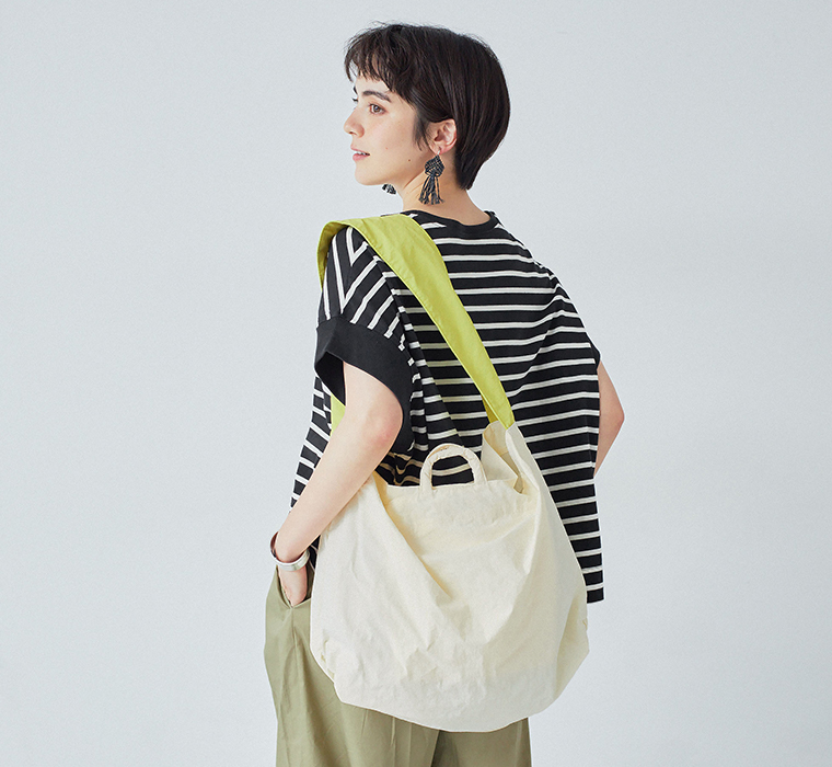 ナイロンリップストラップトートのアイボリー×イエローを肩に掛けた後ろ姿
