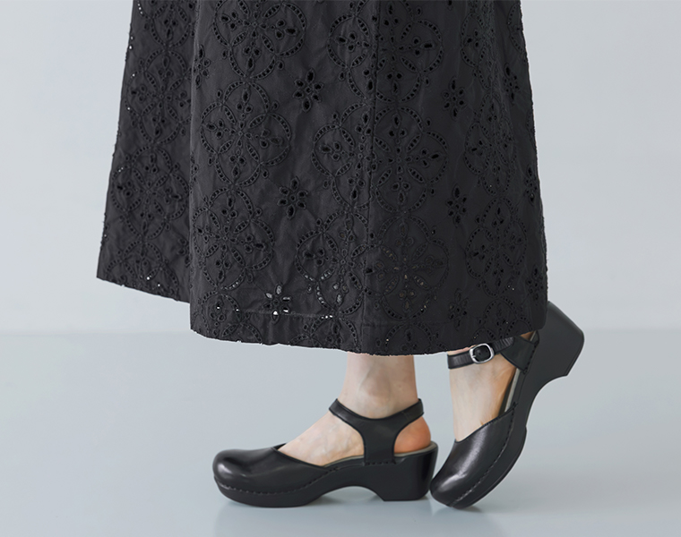 ブラックのカットワークレースワンピースの裾とストラップシューズを履いた足元