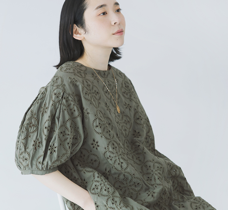 モデルがカーキのカットワークレースワンピースを着て座っている上半身