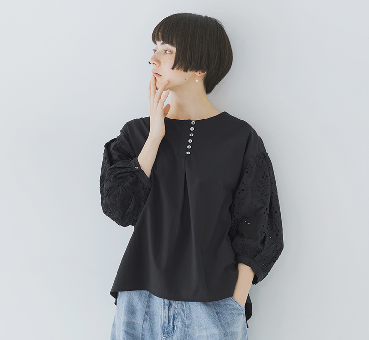 モデルがカットワークレーススリーブブラウスを着てデニムパンツを合わせて上半身を写している