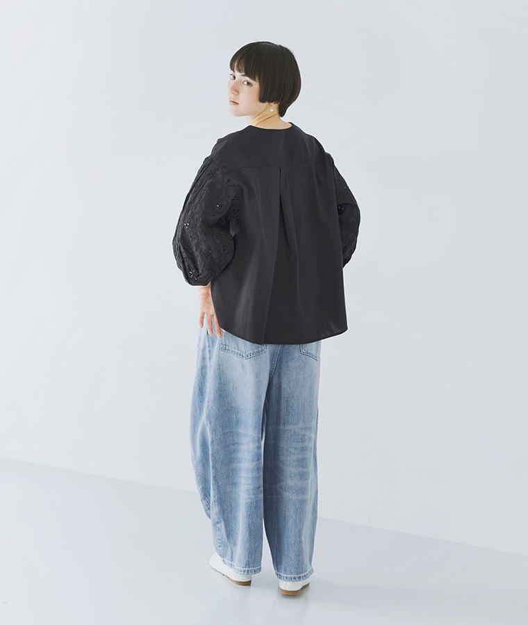 モデルがカットワークレーススリーブブラウスを着て後ろ姿で立っている