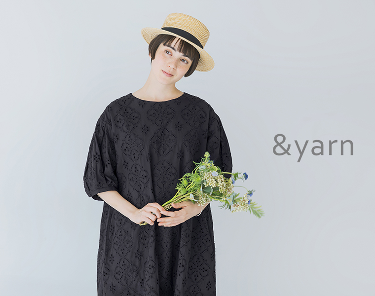 &yarnのブラックのカットワークレースワンピースを着て花束を両手で持っている