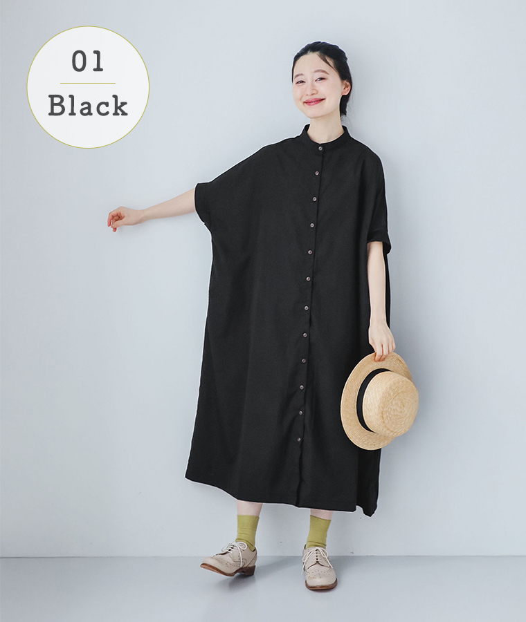 モデルがブラックのリブ袖ドルマンワンピースを着て帽子を持ち正面を向いて立っている