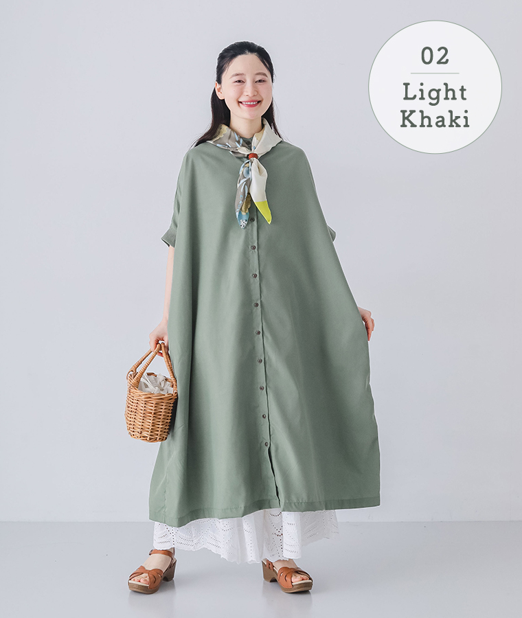 モデルがライトカーキのリブ袖ドルマンワンピースを着てかごバッグを持ち正面を向いて立っている