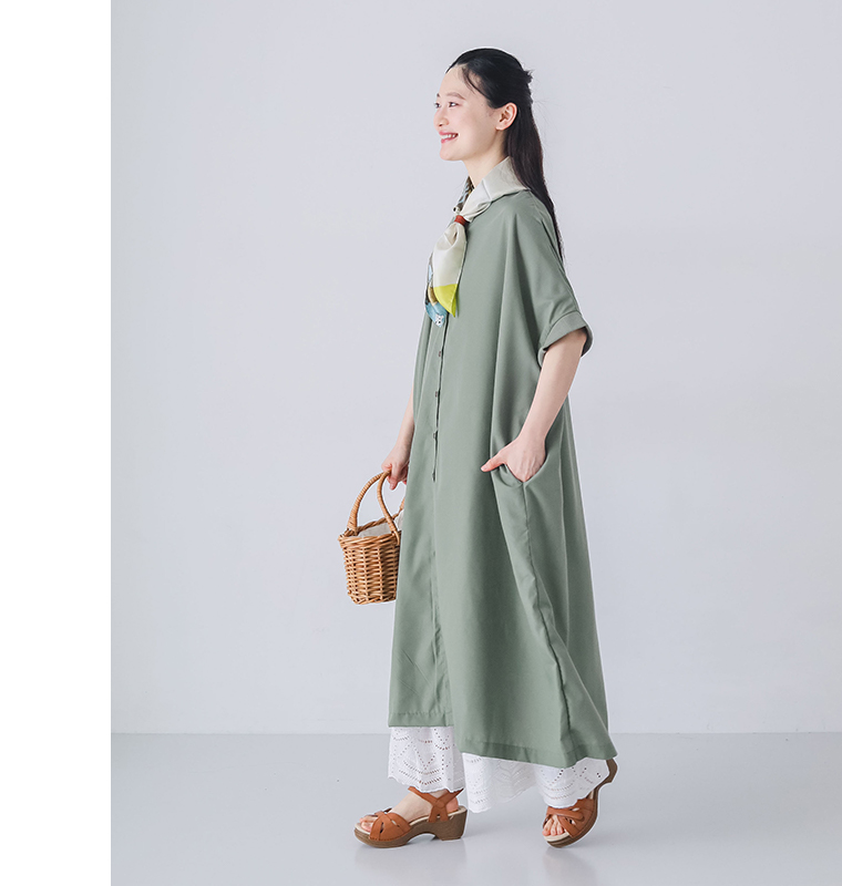 モデルがライトカーキのリブ袖ドルマンワンピースを着てかごバッグを持ち横向きで歩いている