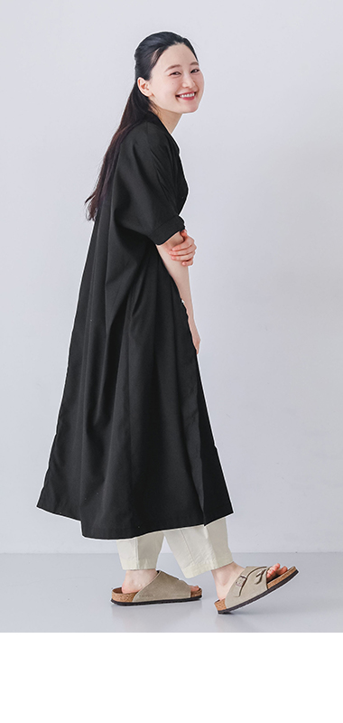 モデルがブラックのリブ袖ドルマンワンピースを着て横向きで歩いている