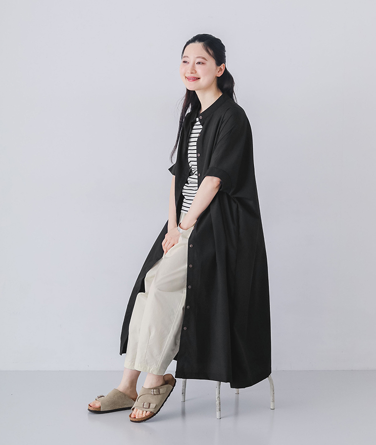 モデルがブラックのリブ袖ドルマンワンピースを着て椅子に座っている