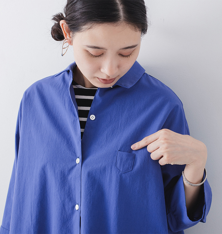 ブルーのシャツを着た人物が胸ポケットのディテールを示している商品画像