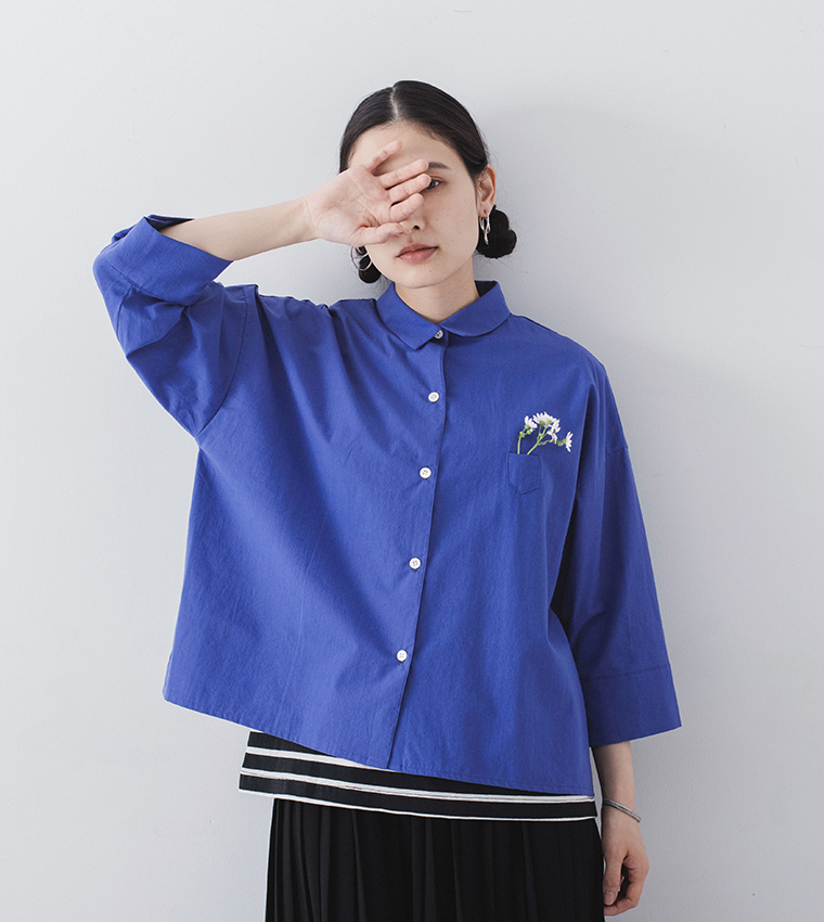 ブルーのシャツを着た人物が胸ポケットに花を挿して立つ商品イメージ