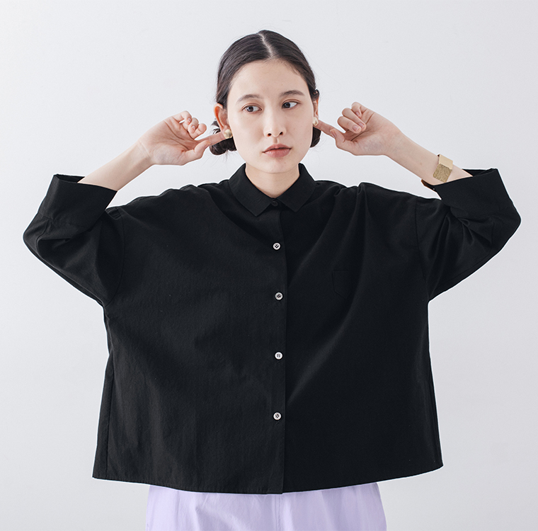 ブラックのシャツを着た人物がイヤーアクセサリーに手を添える着用ディテール画像