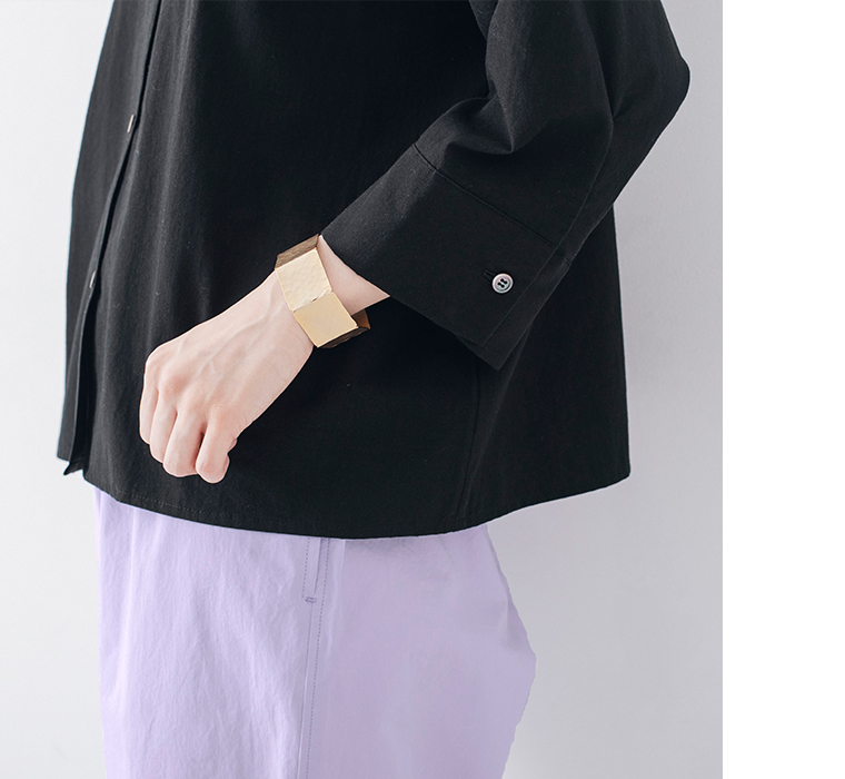 ブラックのシャツとラベンダーパンツにゴールドバングルを合わせた手元ディテール画像