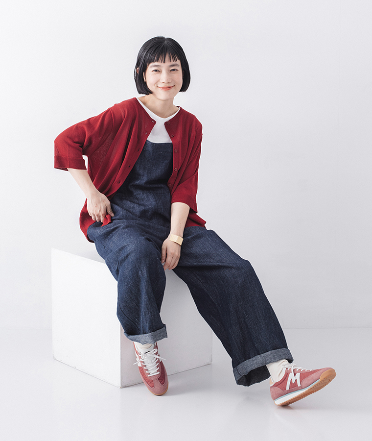 モデルがメスタリのライトマホガニーのスニーカーを履いて座っている全身